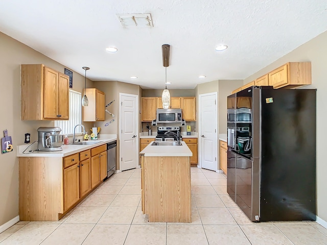 kitchen featuring pendant lighting, an island with sink, light tile patterned floors, sink, and stainless steel appliances