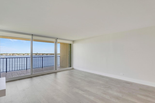 unfurnished room with light hardwood / wood-style floors and a wall of windows