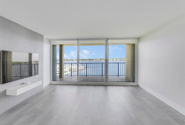 unfurnished living room featuring a water view and expansive windows