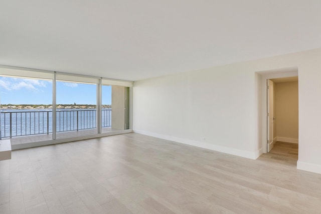 spare room with a water view and a wall of windows