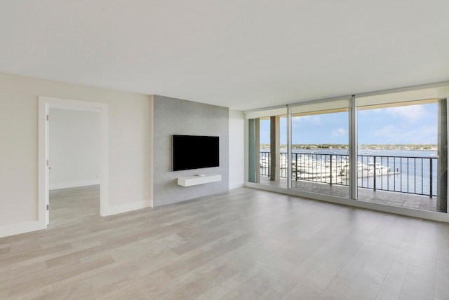 unfurnished living room with a fireplace, floor to ceiling windows, and light hardwood / wood-style floors