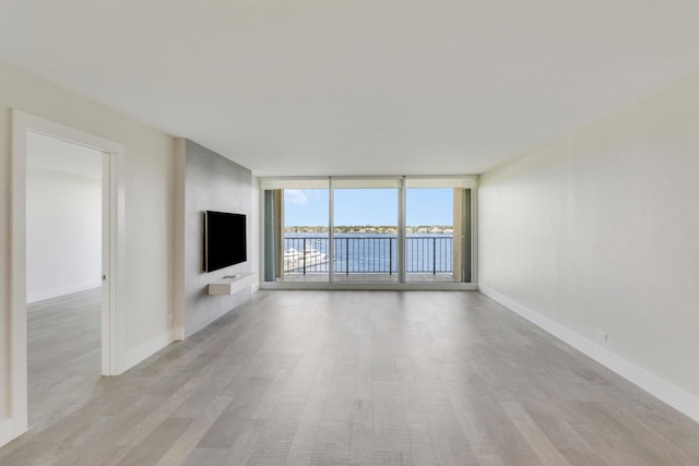 unfurnished living room featuring a wall of windows, light hardwood / wood-style floors, and a large fireplace