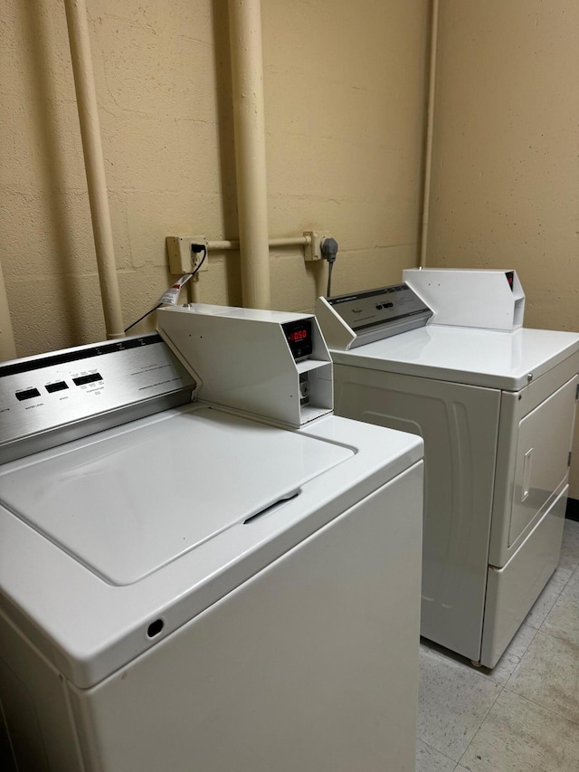 laundry area with washer and clothes dryer and light tile patterned floors