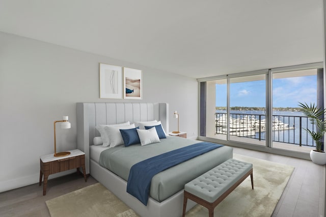 bedroom with wood-type flooring, a water view, access to outside, and floor to ceiling windows