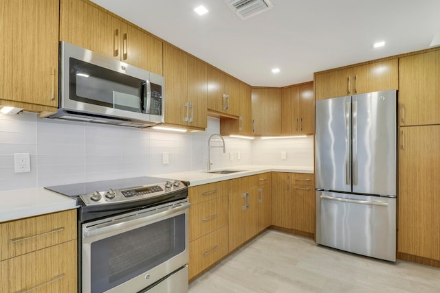 kitchen featuring sink, appliances with stainless steel finishes, backsplash, and light hardwood / wood-style floors