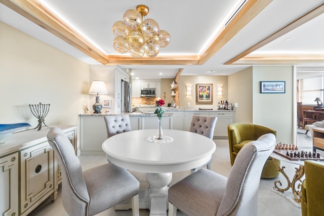 dining room featuring a raised ceiling, an inviting chandelier, and sink