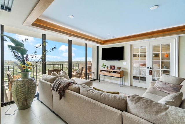 living room featuring a healthy amount of sunlight, a raised ceiling, light tile patterned flooring, and french doors