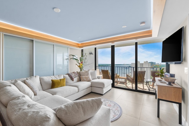 tiled living room featuring a tray ceiling and floor to ceiling windows