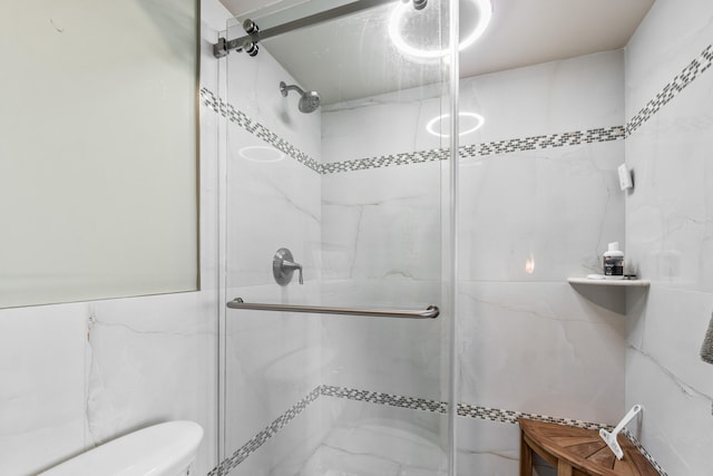 bathroom featuring tile walls, toilet, and a shower with shower door