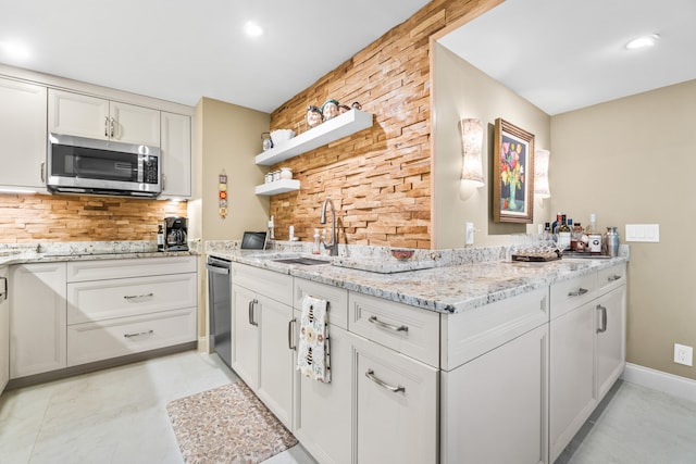 kitchen featuring backsplash, stainless steel appliances, light stone counters, sink, and white cabinets