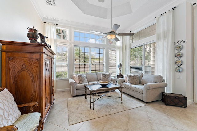 tiled living room with ceiling fan, a tray ceiling, ornamental molding, and a wealth of natural light