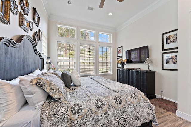 bedroom with a textured ceiling, wood-type flooring, crown molding, and ceiling fan