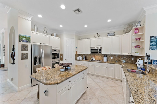 kitchen with stainless steel appliances, light stone counters, a center island, and sink