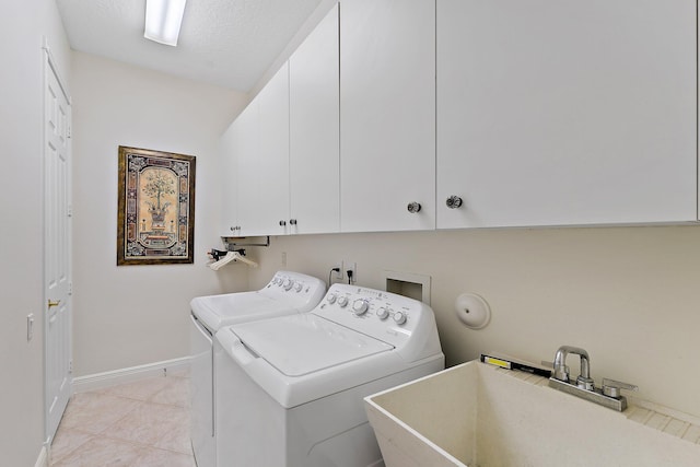 clothes washing area with light tile patterned floors, sink, a textured ceiling, cabinets, and washing machine and dryer