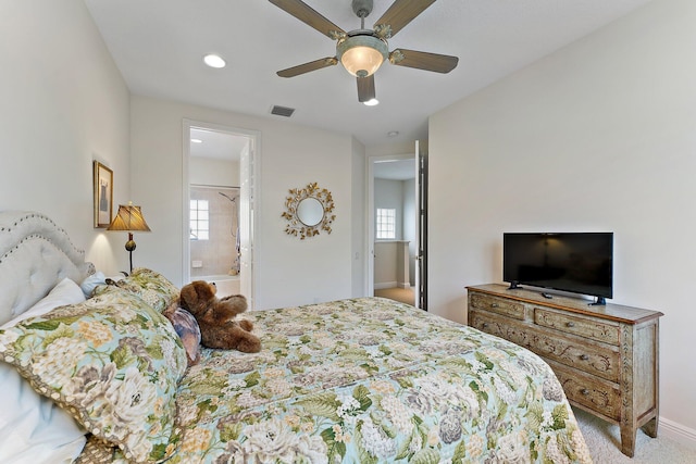 bedroom featuring ceiling fan, light colored carpet, and ensuite bathroom