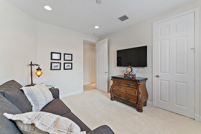 living area featuring light colored carpet and a textured ceiling