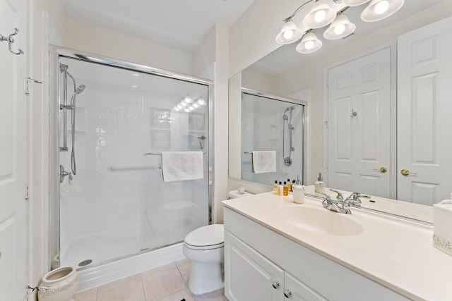 bathroom featuring tile patterned flooring, vanity, toilet, and a shower with shower door