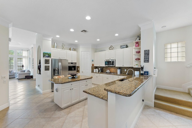 kitchen featuring sink, kitchen peninsula, decorative backsplash, stainless steel appliances, and dark stone countertops