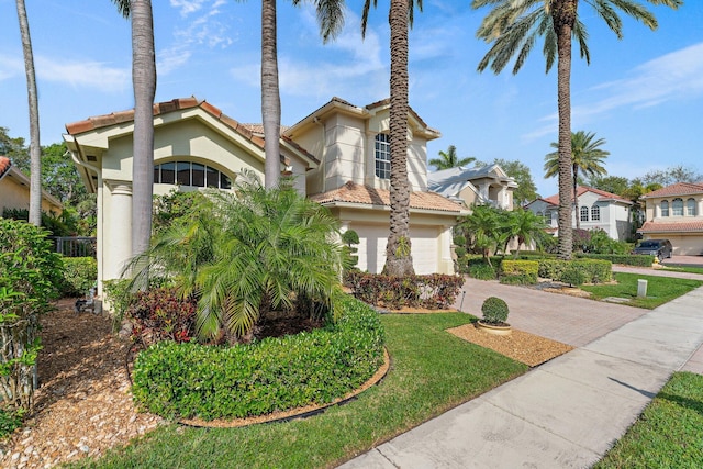 mediterranean / spanish house with a garage and a front lawn