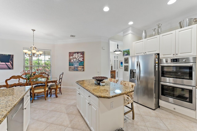 kitchen with white cabinets, stainless steel appliances, light stone countertops, and a kitchen island