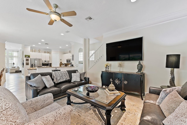 tiled living room featuring crown molding and ceiling fan