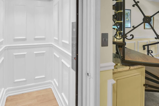 interior details with elevator and hardwood / wood-style flooring