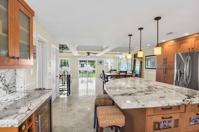 kitchen featuring light stone countertops, stainless steel refrigerator with ice dispenser, ceiling fan, wine cooler, and hanging light fixtures