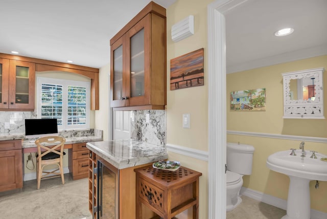 kitchen featuring light stone countertops, decorative backsplash, built in desk, and sink