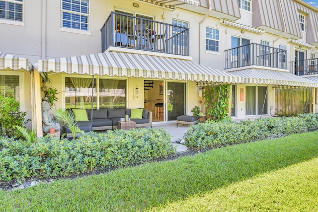 back of house featuring a lawn, outdoor lounge area, and a balcony