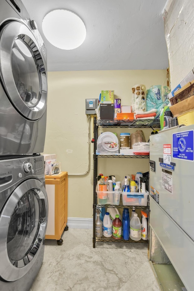 washroom featuring stacked washer / dryer and cabinets