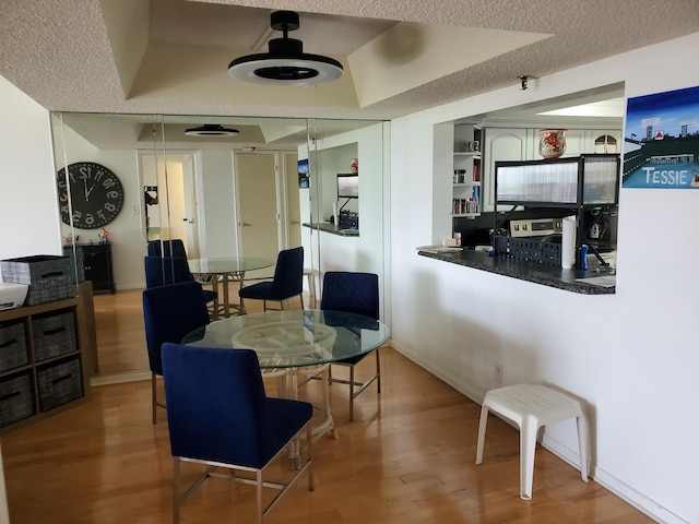 dining room featuring hardwood / wood-style flooring, a raised ceiling, and a textured ceiling