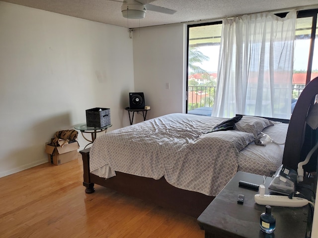 bedroom with ceiling fan, hardwood / wood-style flooring, access to exterior, and multiple windows