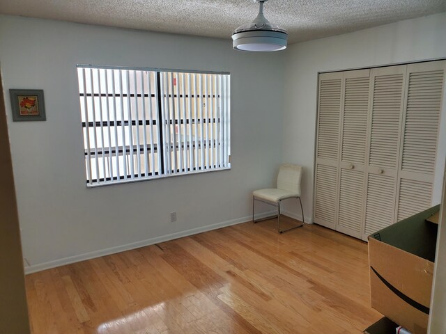 bedroom with light hardwood / wood-style floors, a closet, and a textured ceiling