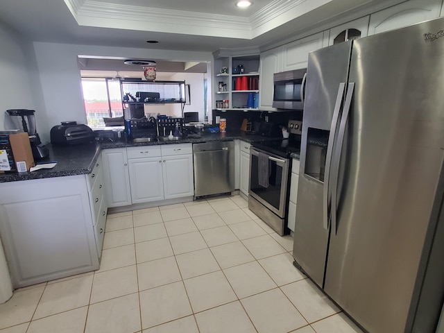 kitchen featuring ornamental molding, white cabinetry, a tray ceiling, and stainless steel appliances