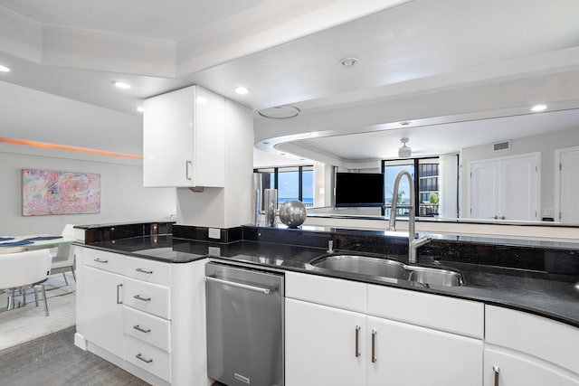 kitchen with dark stone countertops, white cabinetry, sink, wood-type flooring, and stainless steel dishwasher