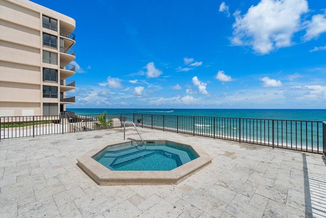 view of pool with a water view, a community hot tub, and a patio