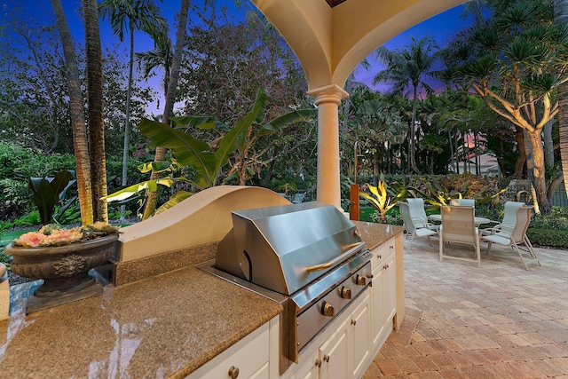 patio terrace at dusk featuring area for grilling