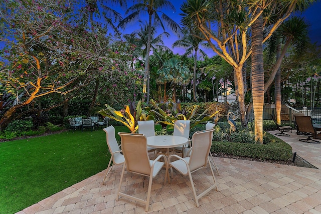 patio terrace at dusk featuring a yard