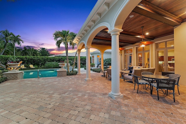 patio terrace at dusk featuring french doors, a fenced in pool, and ceiling fan