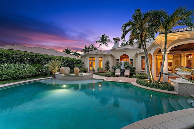 pool at dusk with a patio area