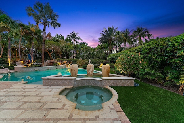 pool at dusk with a lawn and an in ground hot tub