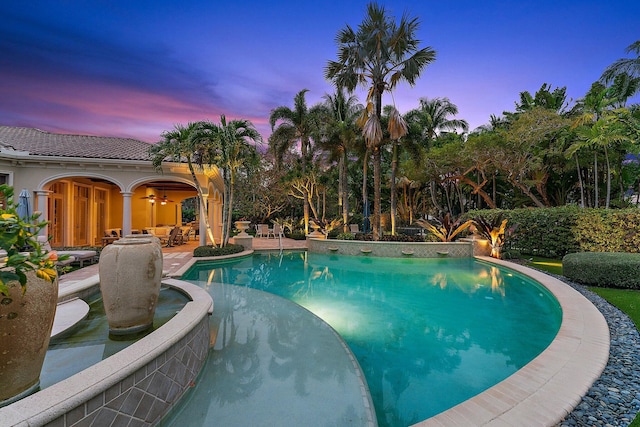 pool at dusk featuring a patio area