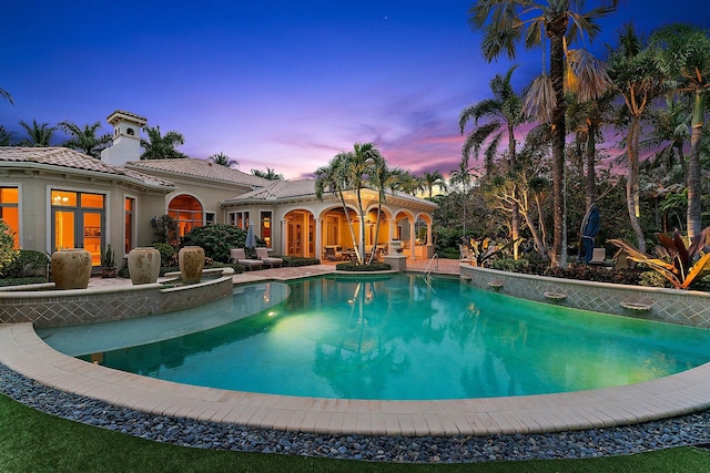 pool at dusk featuring a patio area