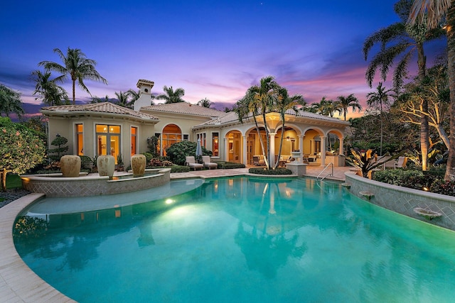 pool at dusk featuring a patio area and french doors