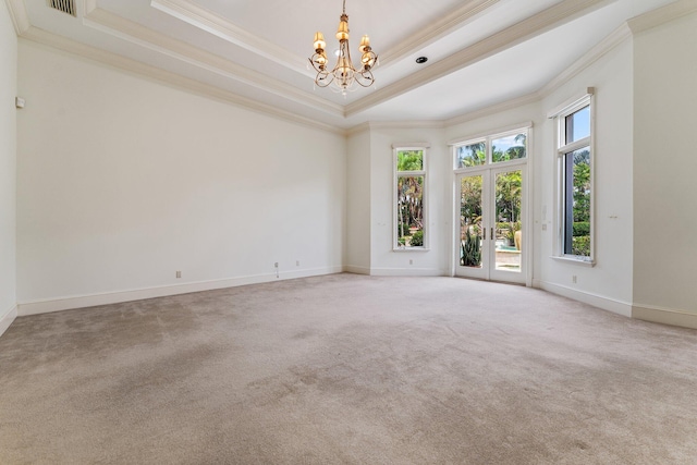 unfurnished room with light carpet, crown molding, a tray ceiling, and a notable chandelier