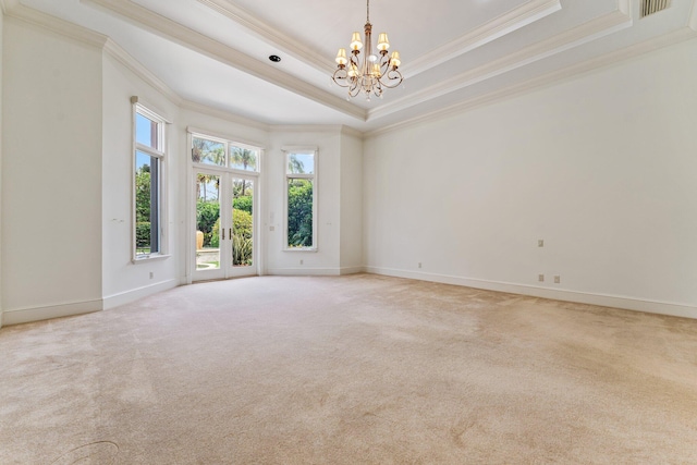 carpeted empty room with ornamental molding, a raised ceiling, and a notable chandelier