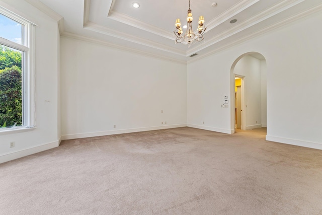 spare room with a tray ceiling, a notable chandelier, a wealth of natural light, and light colored carpet