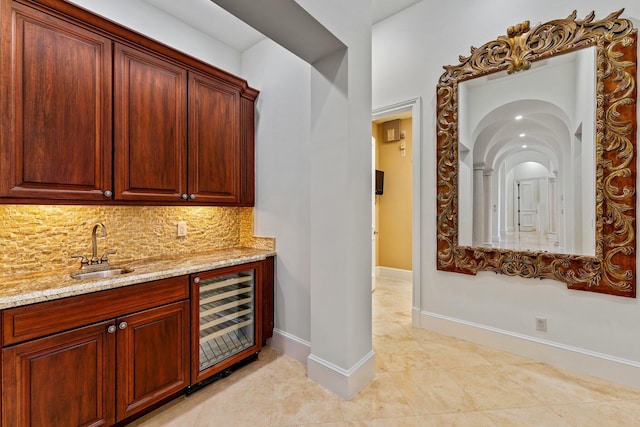 kitchen featuring beverage cooler, light stone countertops, backsplash, and sink