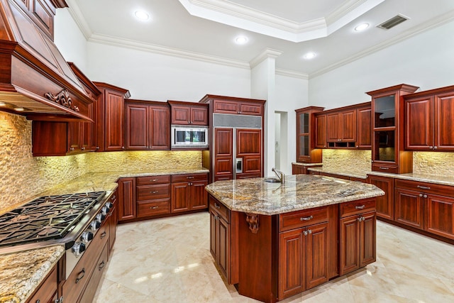 kitchen with a center island, crown molding, light stone countertops, built in appliances, and decorative backsplash