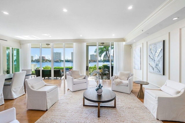 living room with a water view, ornamental molding, and light wood-type flooring